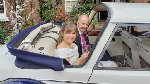 Bride and Groom seating inside vintage-style Royale windsor wedding car with roof down posing for photos