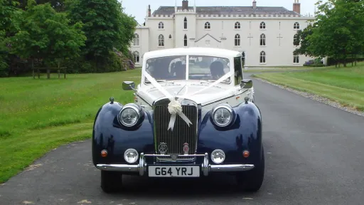 Front view Blue and Ivory vintage-style Royale Windsor with White ribbons and bows on top of its large front chrome grill