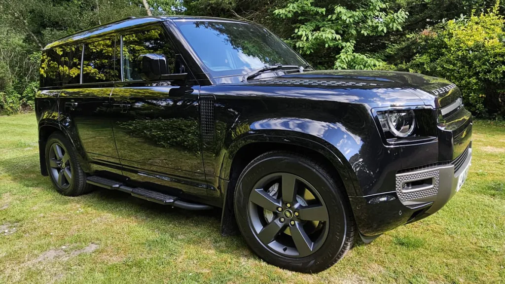 Front right side view of Black Land Rover Defender with black alloy wheels