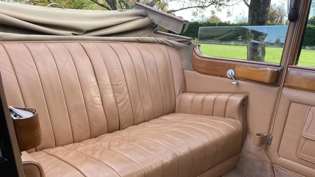rear interior forward facing bench seat inside vintage rolls-royce phantom with rear convertible roof open