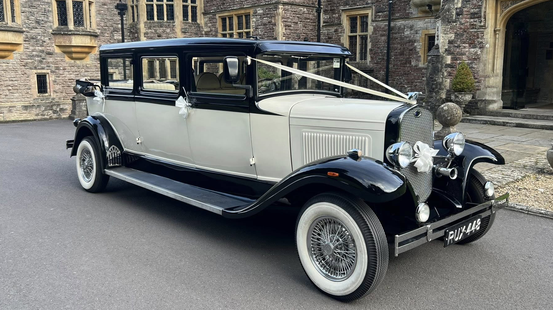 Old English White Bramwith Limousine with black wheel arches and black roof dressed with with ribbons across the bonnet