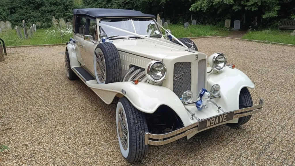 Beauford convertible dressed with Ivory ribbons and black soft top roof closed parked on a gravel road