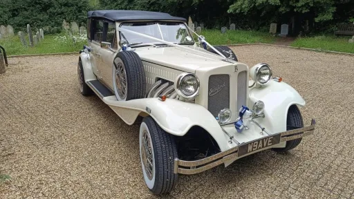 Beauford convertible dressed with Ivory ribbons and black soft top roof closed parked on a gravel road