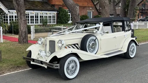 Left side view of Beauford convertible with black soft top roof, ivory ribbons, white wall tires and side-mounted spare wheel.