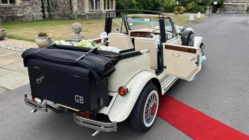 Rear view of Beauford Convertible with black picnic trunk in the rear of the vehicle and red carpet on the floor