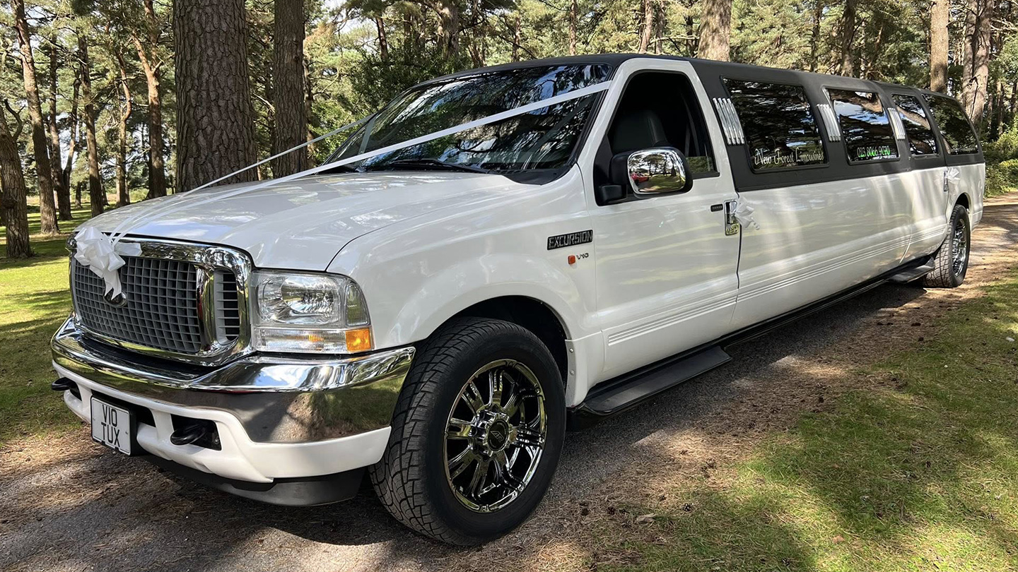 White Ford Excursion Stretched Limousine decorated with white ribbons and bows on front bonnet, large alloy wheels and chrome grill