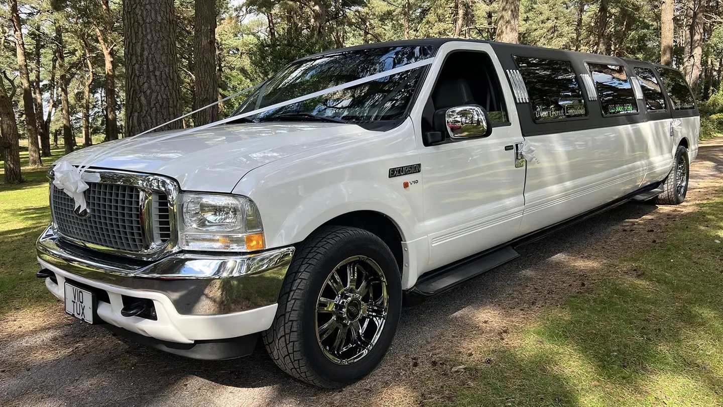 White Ford Excursion Stretched Limousine decorated with white ribbons and bows on front bonnet, large alloy wheels and chrome grill
