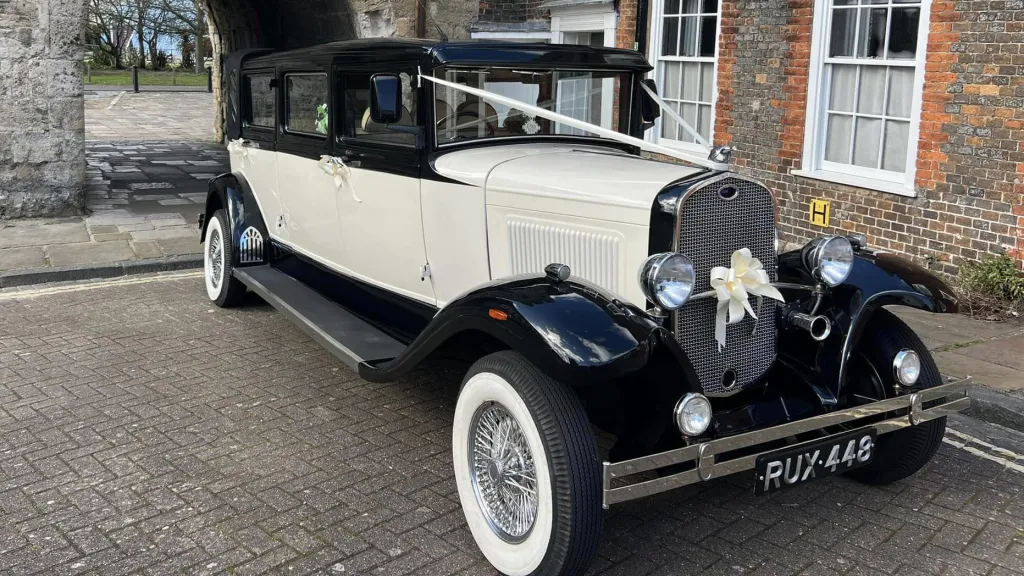 Front view vintage style Bramwith in Ivory and Black with large white wall tires, fron chrome bumper and ivory bow in the middle of the front chrome grill