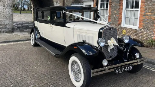 Front view vintage style Bramwith in Ivory and Black with large white wall tires, fron chrome bumper and ivory bow in the middle of the front chrome grill