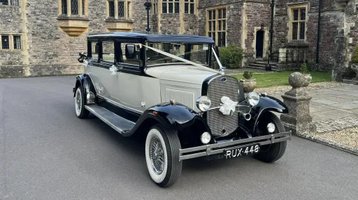 Black & Ivory Bramiwth laundaulette with white ribbons and bows in front of Rhinefoield House Hotel in New Forest