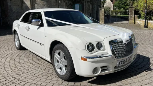 Front right view of White Chrysler 300c saloon car parked in street of Southampton and dressed with white ribbons