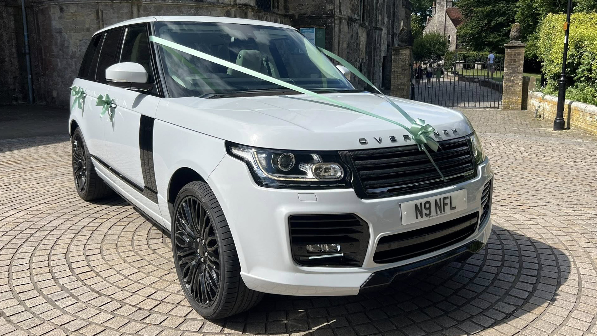 White Range Rover with black alloy wheels parked in street of Southampton and dressed with green ribbons