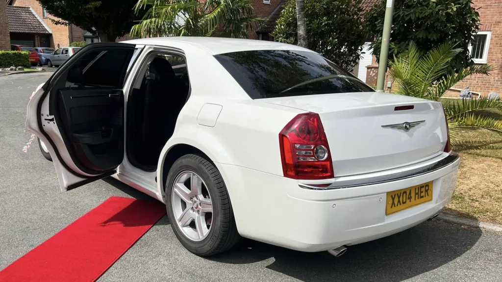 Rear left view of white chrysler 300c saloon with rear open door open and red carpet