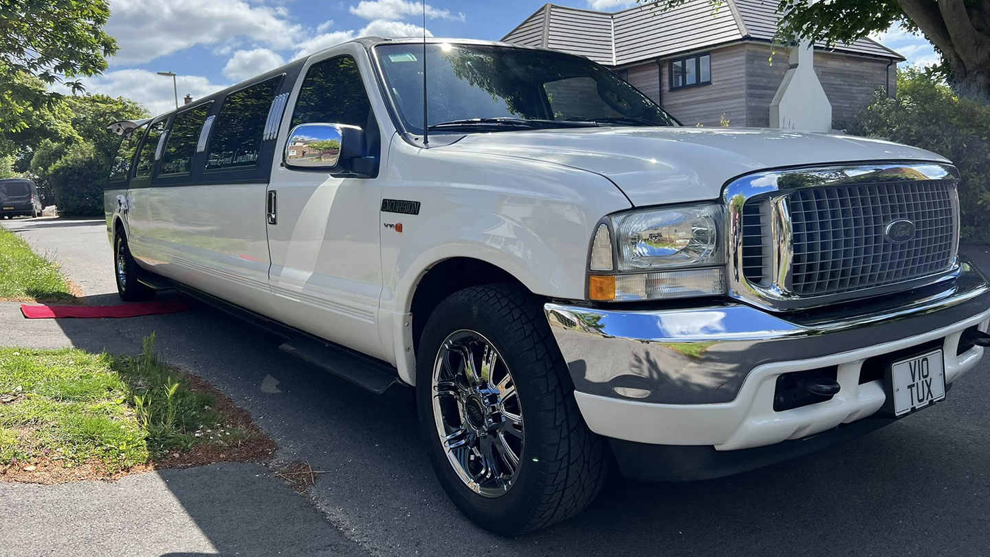 Ford Excursion Stretched Limousine with large alloy wheels parked in the street in front of a house with red carpet