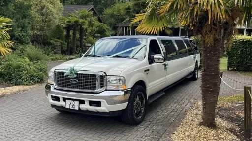 Ford Excursion Stretched Limousine dressed with green ribbons and bows parked at a wedding venue with palm trees