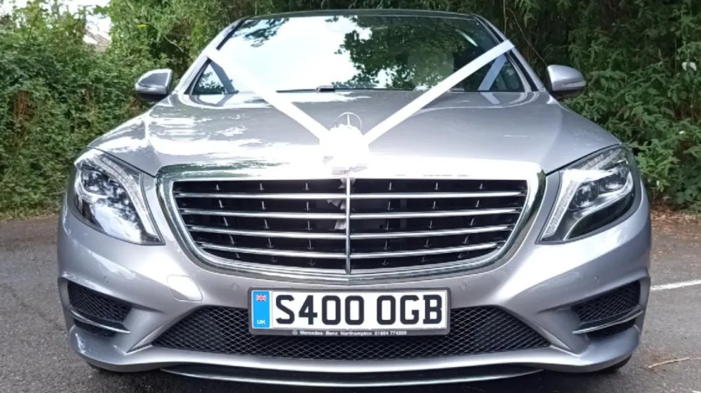 Full front view of Silver Mercedes with white bow on top of the chrome grill