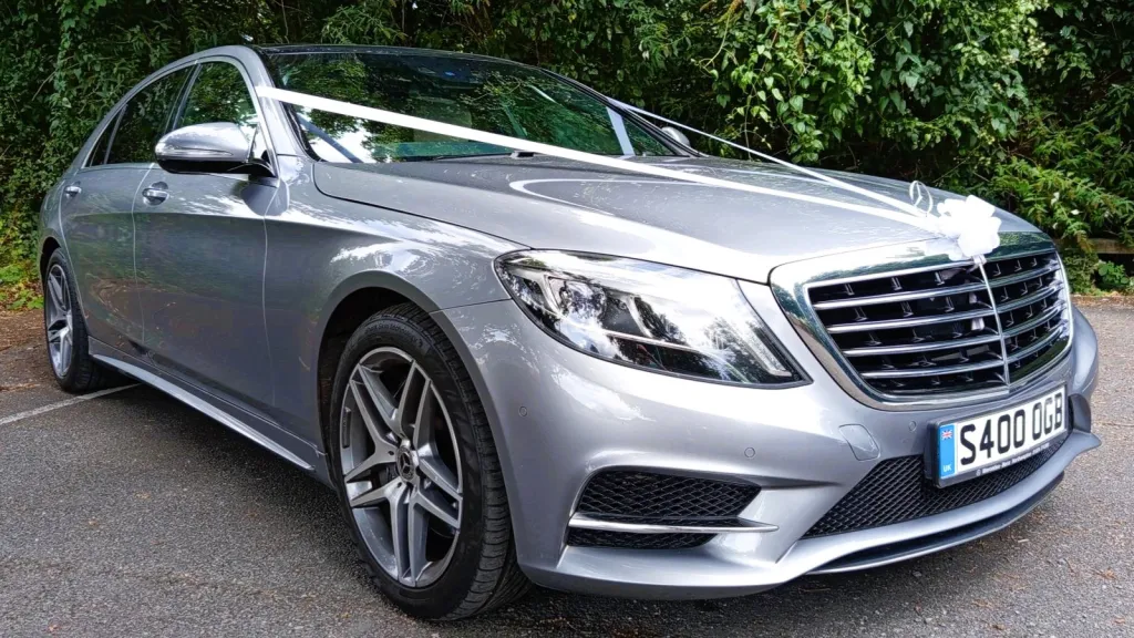 Silver Mercedes S-class dressed with white wedding ribbons across the bonnet and a white bow on top of the chrome grill