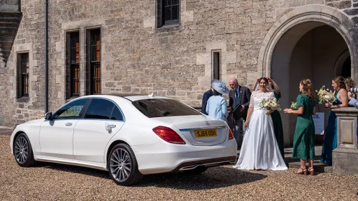 White Mercedes at a real wedding with Bride and wedding guests in the background