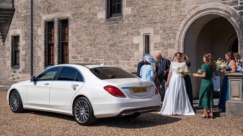 White Mercedes at a real wedding with Bride and wedding guests in the background