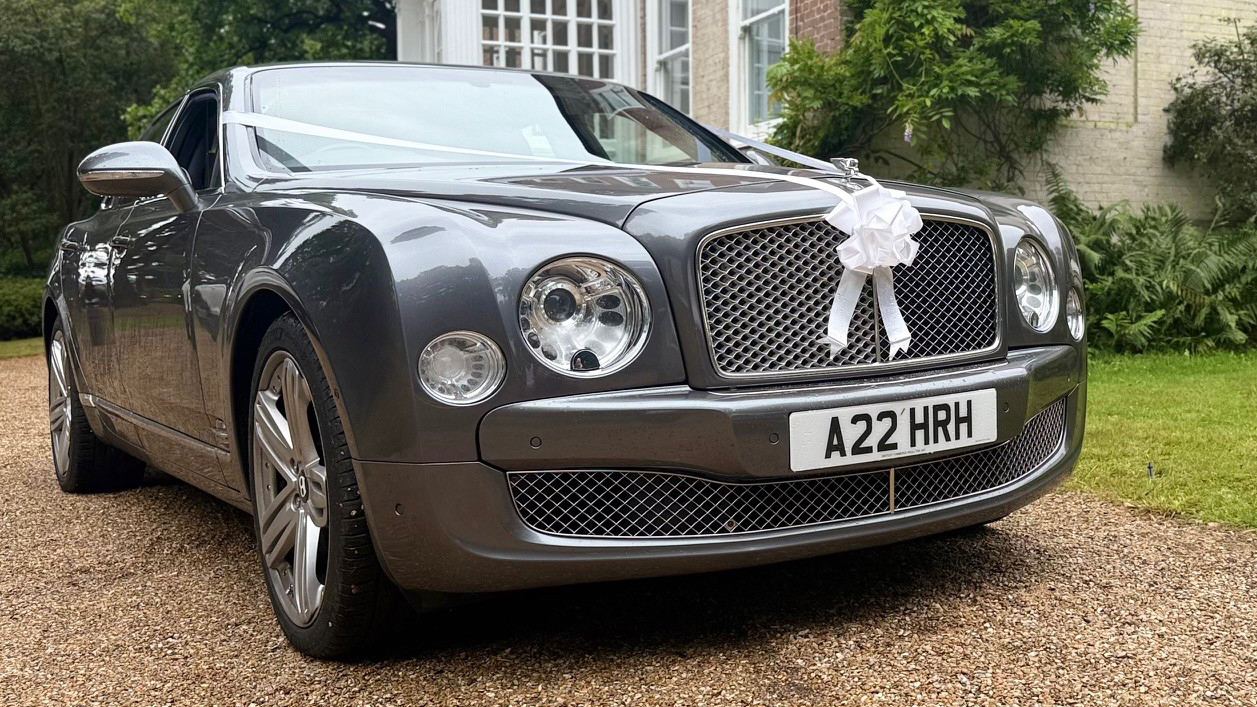 Grey Bentley Mulsanne with large alloy wheels finished in chrome and dressed with white ribbons and bows