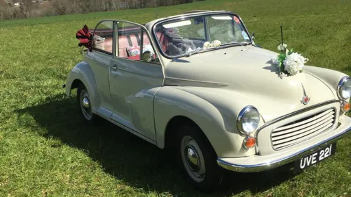 Front view of classic Morris Minor with convertible roof open and decorated with white wedding flower on the front bonnet