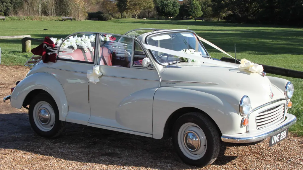 Classic Morris Minor in Old English White with Convertible roof open and decorated with ribbons accros front bonnet and flowers on rear parcel shelf