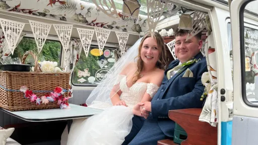 Bride and Groom seating inside a classic VW Campervan decorated with wedding decoration