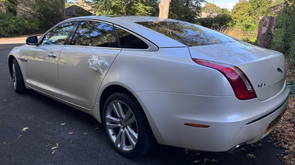 Rear view of White White Jaguar XJ with LWB logo, rear privacy tinted windows
