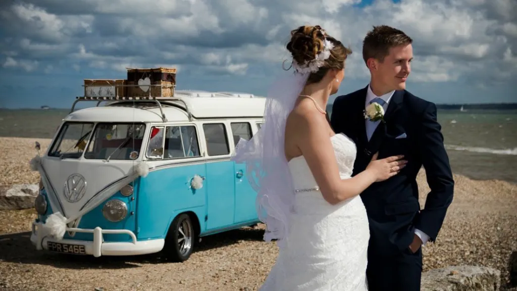 Bride and Groom holding each others with a Blue ~& White classic VW campervan in the background