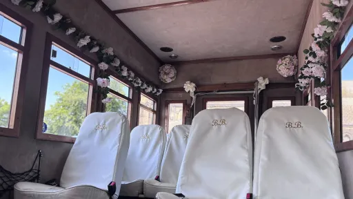 Vintage style interior look insidde Asquith Bus decorated with wedding style white flowers and white seat covers on the forward facing seats