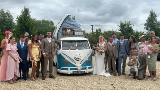 Wedding party standing around a classic Blue and White VW campervan