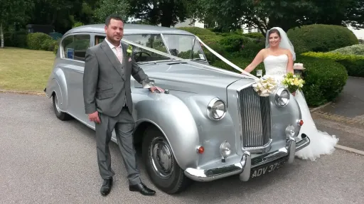 Silver Austin Princess wedding car with Bride and Groom standing on both side of the vehicle