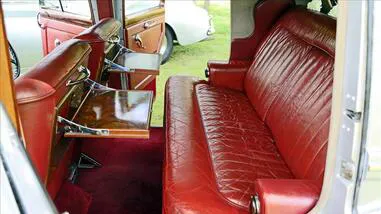 Rear cabin of a Bentley R-Type with rich red leather seats and polished wood trim