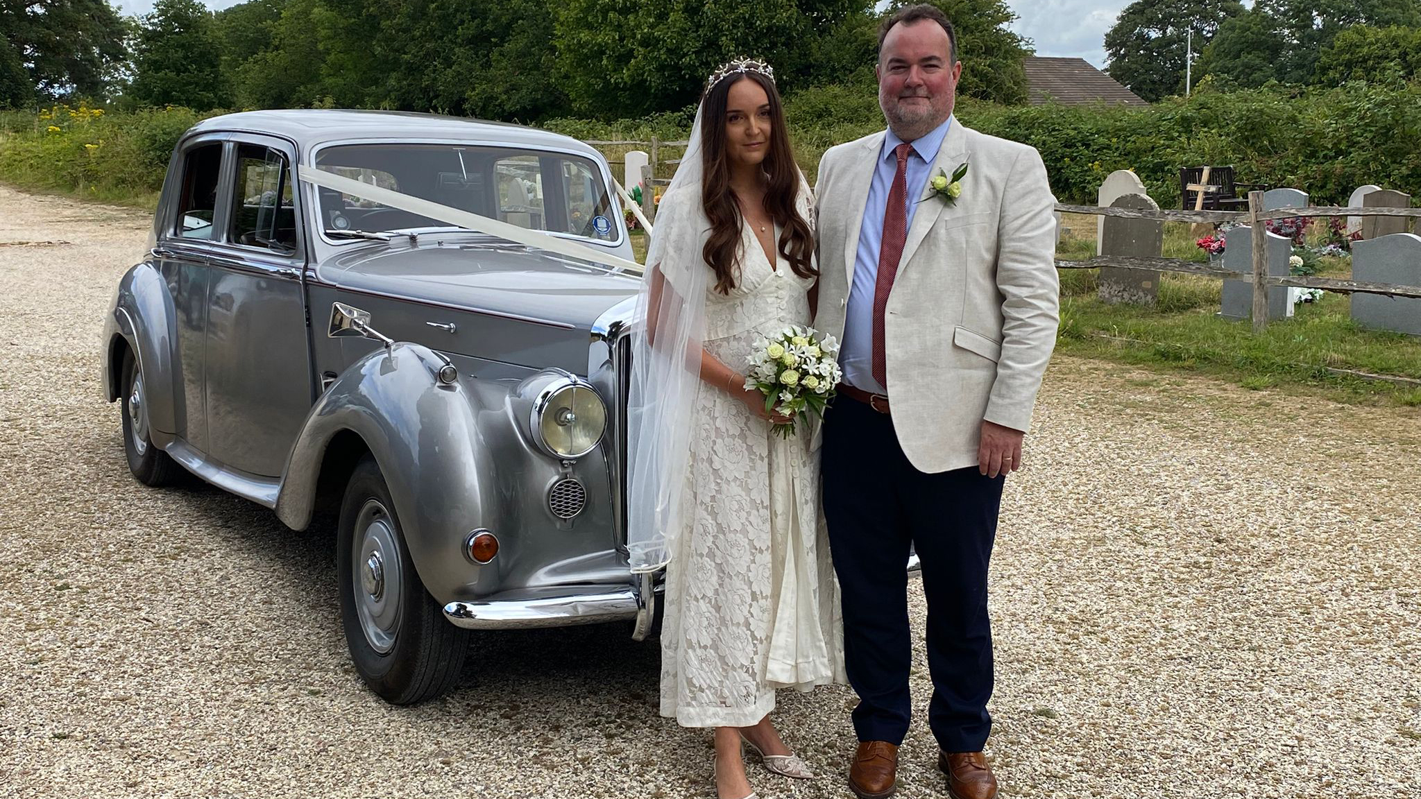 Bride and her father standing beside a silver Bentley R-Type classic car