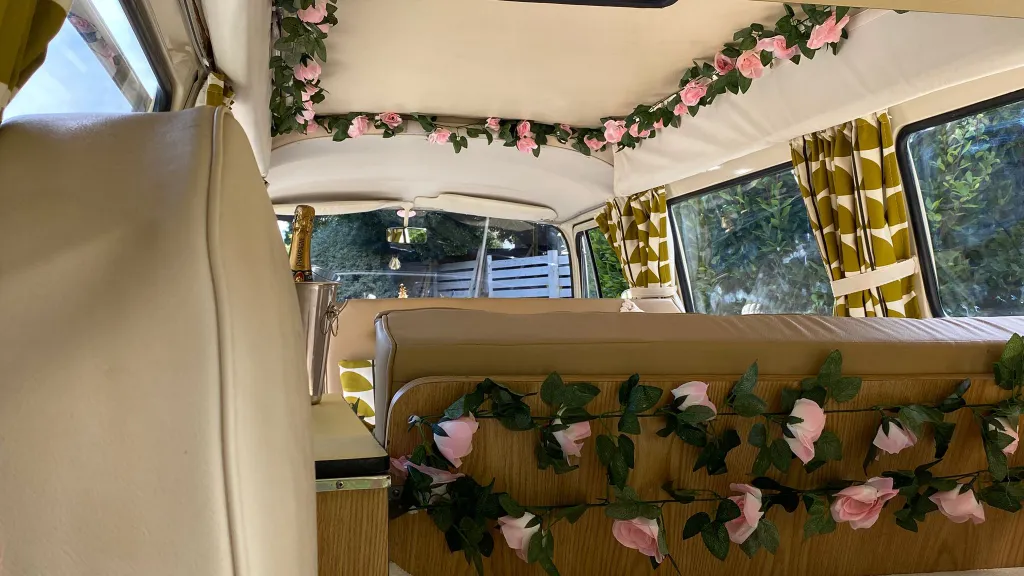Classic VW campervan interior decorated with artificial roses and gold curtains