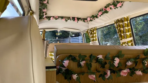 Classic VW campervan interior decorated with artificial roses and gold curtains