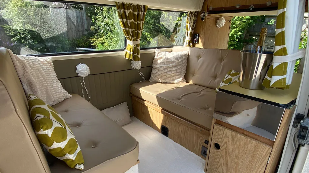 Classic VW campervan rear seating area with floral garlands and retro patterned cushions