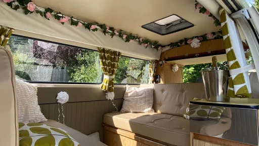 Wedding-themed interior of a classic VW campervan with bunting, roses and champagne bucket