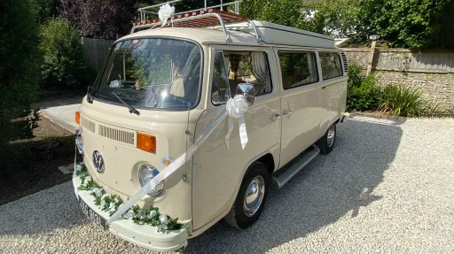 Cream classic VW campervan decorated with flowers parked in the sun