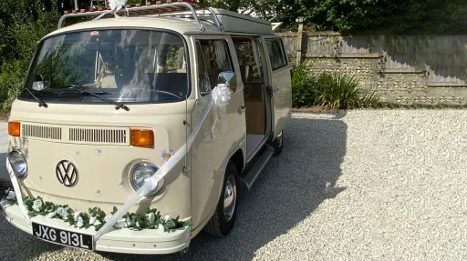 Front view of a cream VW campervan wedding vehicle with floral decorations
