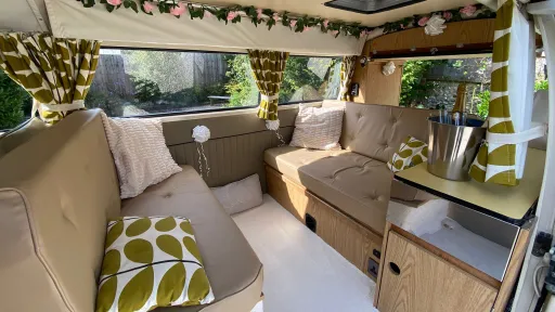Cream leather rear interior lounge area of a classic VW campervan with patterned cushions