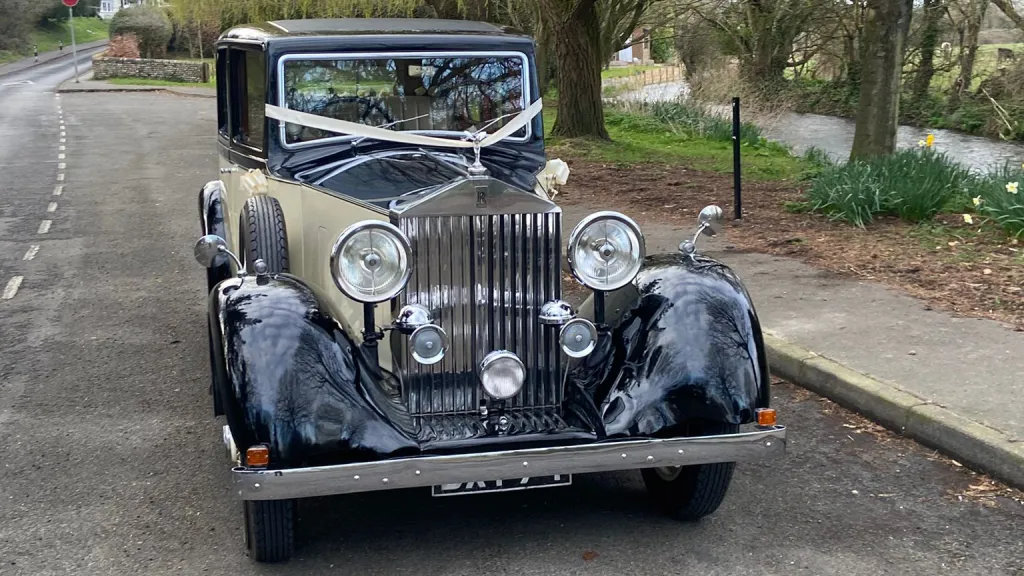 Front view of a vintage Rolls-Royce 20/25 adorned with wedding ribbons