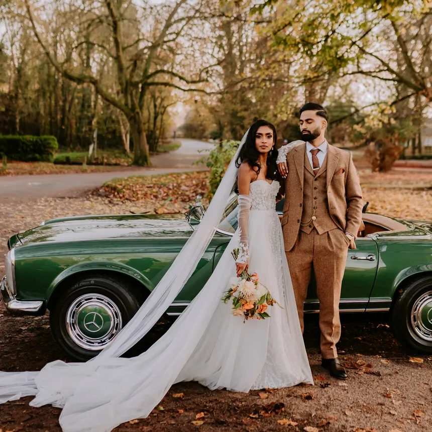 Bride and groom posing with a dark green Mercedes-Benz SL classic convertible in an Autumn background
