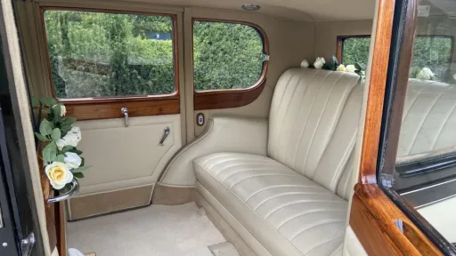Rear cabin of a vintage Rolls-Royce 20/25 with cream seats and wood trim