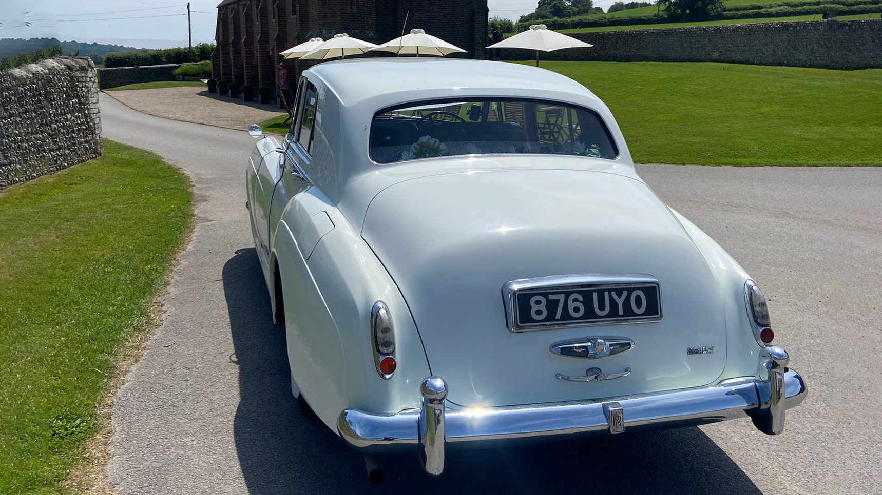 Rear view of a white Rolls-Royce Silver Cloud parked on a country lane