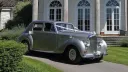 Silver Bentley R-Type classic car parked on grass outside a wedding venue