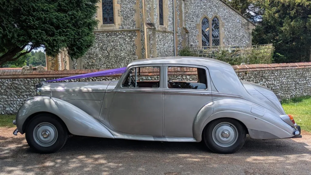 Silver Bentley R-Type with purple wedding ribbons stretched across the bonnet