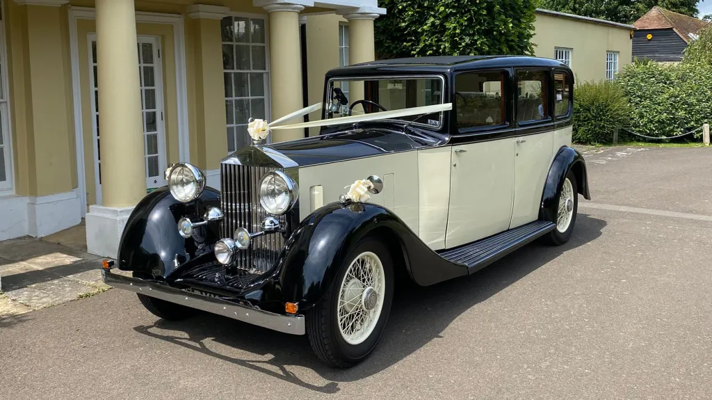 Vintage Rolls-Royce 20/25 with white wedding ribbons outside a venue