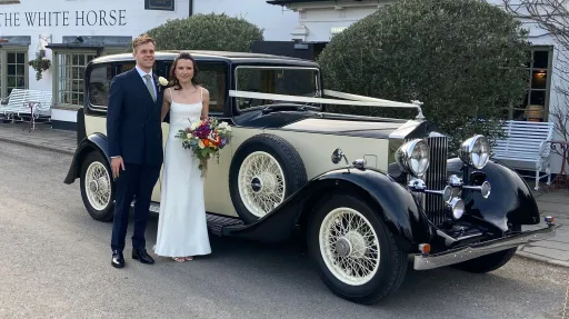 Wedding couple standing and smiling next to a vintage Rolls-Royce 20/25