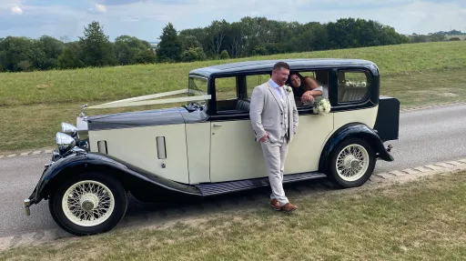 Wedding couple posing next to the front of a vintage Rolls-Royce 20/25